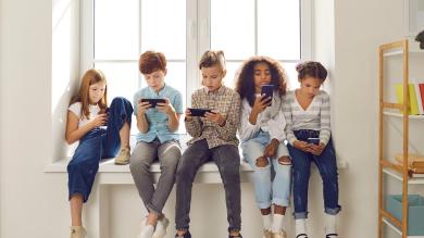 Kinder auf Fensterbank sitzend mit Smartphones, In-App-Käufe